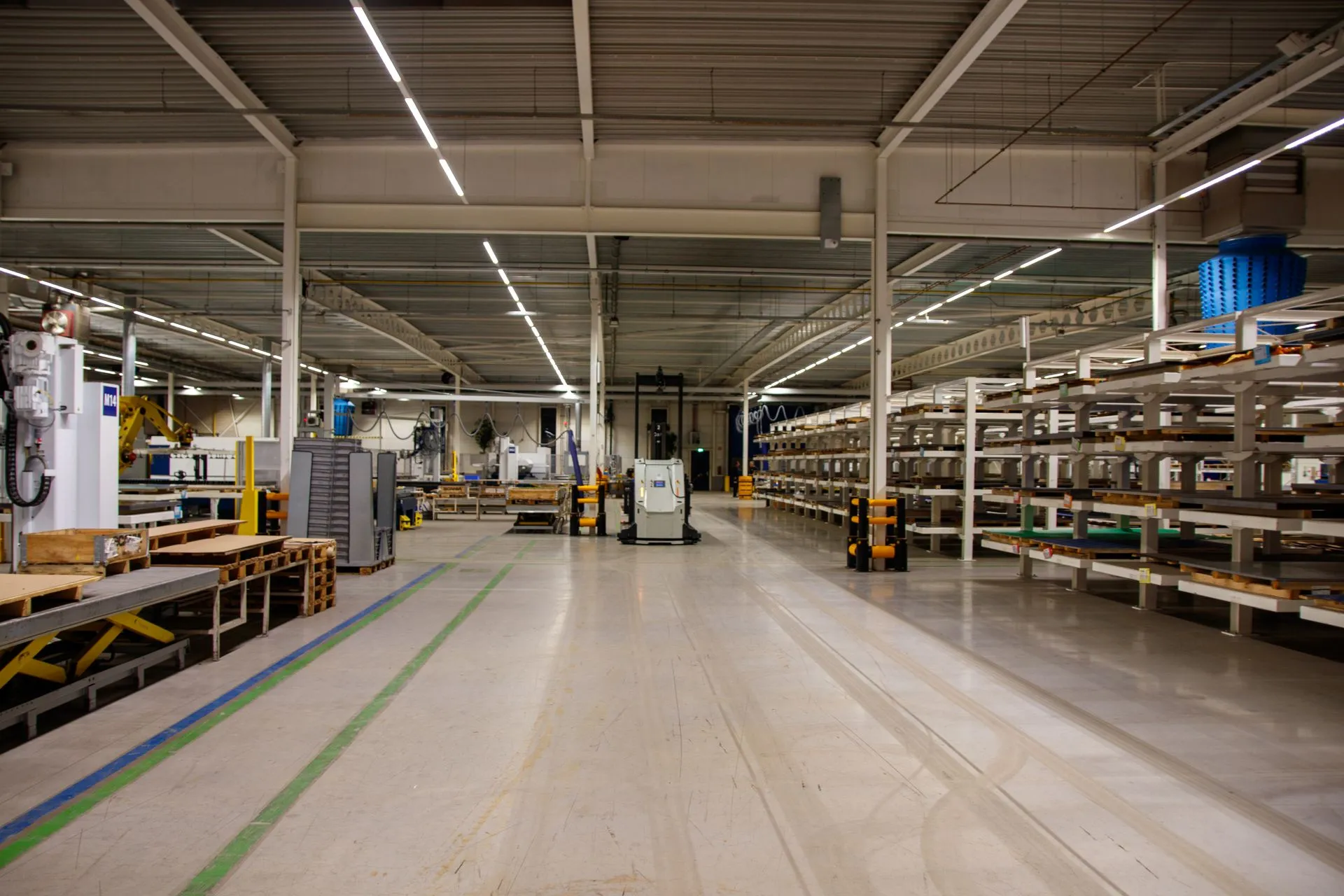 Interior de planta moderna con pasillo central, maquinaria y racks de almacenaje